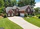 Charming two-story red brick home with a well-manicured lawn, driveway and attached two-car garage at 220 Lavender Oasis, Peachtree City, GA 30269