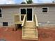 Back of the house with light brown siding, concrete foundation, a sliding glass door, and wooden stairs at 436 Laurel Trce, Carrollton, GA 30116