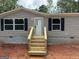 A close up of the front entrance showing the new wooden steps, gray siding, black shutters, and block foundation at 436 Laurel Trce, Carrollton, GA 30116
