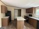 Modern kitchen featuring dark wood cabinets, black appliances, granite countertops, and a center island at 436 Laurel Trce, Carrollton, GA 30116
