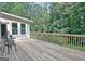 Back deck featuring wood flooring, a table and chairs, and views of lush trees, perfect for relaxing outdoors at 110 Heatherwood Dr, Fayetteville, GA 30215