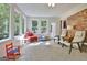 Sunroom featuring a red brick accent wall and multiple windows for natural lighting at 110 Heatherwood Dr, Fayetteville, GA 30215
