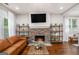 Cozy living room showcasing a stone fireplace with built-in shelves, hardwood floors, and natural light at 9148 Tarnwood Dr, Villa Rica, GA 30180