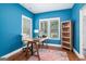 Office with blue walls, hardwood floors, a colorful rug, natural light, and a built-in shelf at 9148 Tarnwood Dr, Villa Rica, GA 30180