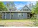 A view of the blue house exterior with multiple windows and a screened porch overlooking the lush green backyard at 9148 Tarnwood Dr, Villa Rica, GA 30180