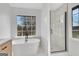Modern bathroom featuring a soaking tub, glass-enclosed shower, and large windows providing natural light at 3797 Churchill Sw Dr, Marietta, GA 30064