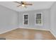 Bright bedroom with wood-look floors, ceiling fan, and two large windows offering views of the neighborhood at 3797 Churchill Sw Dr, Marietta, GA 30064