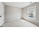 This bedroom features neutral paint, carpet, a window overlooking the neighborhood and white doors and trim at 6448 Mobilis Ct, Sugar Hill, GA 30518