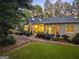 Back exterior with a covered patio, stone pathway, manicured lawn, and mature landscaping offering a serene setting at 107 Calloway Xing, Peachtree City, GA 30269