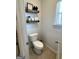 Bathroom featuring a toilet, decorative shelves, and a window at 5257 Shorthorn Way, Powder Springs, GA 30127