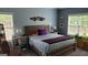 Comfortable bedroom with wood bed frame, gray walls, and natural light from the windows at 223 Overland Trl, Mcdonough, GA 30252