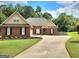 Charming brick home featuring a manicured lawn, long driveway, and traditional architectural details at 223 Overland Trl, Mcdonough, GA 30252