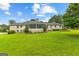 Spacious backyard view of a brick home with screened-in porch, mature trees, and a well-kept lawn at 115 Fernway Dr, Fayetteville, GA 30214