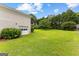 Expansive backyard featuring lush green grass, mature trees, and a white brick house, creating a serene outdoor space at 115 Fernway Dr, Fayetteville, GA 30214