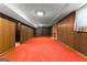 Finished basement with red carpet, paneled walls and a brick fireplace at 115 Fernway Dr, Fayetteville, GA 30214