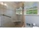 Tile shower with grab bar, frameless glass door, and a window bringing in natural light at 115 Fernway Dr, Fayetteville, GA 30214