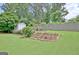 A backyard features a green lawn, wooden fence, flower beds, and a small shed at 332 Aster Ridge Trl, Peachtree City, GA 30269
