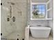 This marble bathroom features a soaking tub under a window, and a glass shower with rain shower head at 332 Aster Ridge Trl, Peachtree City, GA 30269