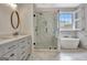 This bright bathroom features a glass shower with marble-style tile, dual vanity and modern soaking tub at 332 Aster Ridge Trl, Peachtree City, GA 30269