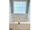 Close up on white bathtub with tile surround and natural light at 116 Cardell Farms Rd, Locust Grove, GA 30248
