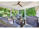 Screened porch with a ceiling fan, table, and covered outdoor furniture overlooking lush trees at 6131 Sparkling Cove Ln, Buford, GA 30518