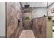 Close-up of the glass-enclosed shower with mixed stone tiling and modern fixtures at 6131 Sparkling Cove Ln, Buford, GA 30518
