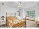 Comfortable bedroom featuring a gold-framed bed, window seat, ceiling fan, and ample natural light at 3245 Bywater Trl, Roswell, GA 30075