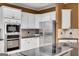 Well-equipped kitchen featuring black countertops, built-in microwave and oven, plus stainless refrigerator at 3245 Bywater Trl, Roswell, GA 30075