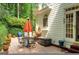 Outdoor patio featuring a dining table, patio umbrella, tiled flooring, potted plants, and lush greenery at 3245 Bywater Trl, Roswell, GA 30075