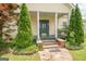 Inviting front porch with green door, framed by manicured evergreen trees and lush ground cover, creates a welcoming entrance at 178 S Old Highway 27, Roopville, GA 30170