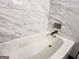 A close up of the bathtub with white marble tiling extending from the floor to the ceiling at 3150 Stratford Green Pl, Avondale Estates, GA 30002