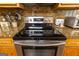 A close-up of the kitchen range with stainless steel features, granite countertops, and wooden cabinets at 280 Ridgemont Dr, Fayetteville, GA 30215