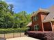 Brick home with a fenced-in yard featuring manicured shrubs and mature trees at 1209 Persimmon Way, Mcdonough, GA 30252