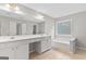 Sunlit bathroom with double sinks, vanity, a window, tub and tiled flooring at 8750 Redford Ln, Suwanee, GA 30024