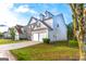Home exterior featuring a two-car garage, dormer windows, and a well-kept lawn at 8750 Redford Ln, Suwanee, GA 30024