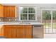 Functional kitchen area features wooden cabinetry, stainless steel dishwasher and sink and a sliding glass door at 8750 Redford Ln, Suwanee, GA 30024