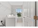 Well-lit laundry room with a window, washer and dryer, shelving and a tiled floor at 8750 Redford Ln, Suwanee, GA 30024