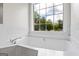 Bathroom featuring a soaking tub with white tile surround and a large window at 501 Llewellyn Ct, Jenkinsburg, GA 30234