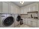 Well-lit laundry room boasts a full-sized washer, dryer, cabinets, countertop, and sink at 825 Chalet Hls, Mcdonough, GA 30253