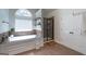 Bright main bathroom featuring a soaking tub, a glass-enclosed shower, and an arched window for natural light at 145 Seawright Dr, Fayetteville, GA 30215