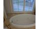 White bathtub with chrome fixtures under arched window with white shutters at 433 Abbey Springs Way, Mcdonough, GA 30253