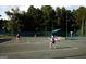 Active tennis courts with players in action, surrounded by well-maintained fencing and lush greenery at 433 Abbey Springs Way, Mcdonough, GA 30253