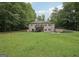 Expansive backyard with lush green grass, mature trees, and a view of the house with a deck at 140 Alford Dr, Fayetteville, GA 30215