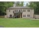Backyard with lush green lawn, trees, and view of the house with a deck and patio at 140 Alford Dr, Fayetteville, GA 30215