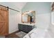Bright bathroom featuring double sinks, white wainscoting, soaking tub, and a rustic sliding barn door at 140 Alford Dr, Fayetteville, GA 30215