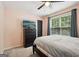 Bedroom features a dark wood bed frame, closet, a window with backyard views, and hardwood floors at 140 Alford Dr, Fayetteville, GA 30215