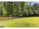 Spacious backyard with lush green lawn is lined with privacy fencing and mature trees at 150 Dean Dr, Tyrone, GA 30290