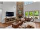 Spacious living room boasts a stone fireplace, wood floors, and a leather couch with views of the pool at 150 Dean Dr, Tyrone, GA 30290