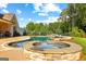 A luxury pool and hot tub with a stone border and plenty of green trees for privacy at 150 Dean Dr, Tyrone, GA 30290
