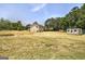 A tan house sits amid an expansive lawn, accompanied by an outbuilding and mature trees on a sunny day at 668 Spring Place Ne Rd, White, GA 30184